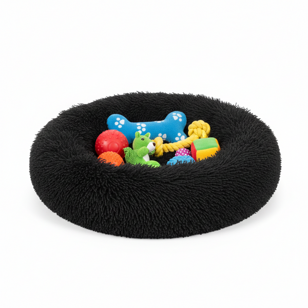 Black fluffy pet bed with colorful dog toys on a white background